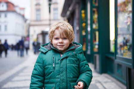 Portrait of little toddler boy walking through the city on cold winter day.の写真素材
