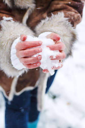 Hands of woman with snow heart in winterの写真素材