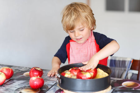 Adorable little boy helping and baking apple pie in home''s kitchen, indoor.の写真素材