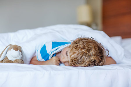 Adorable child sleeping and dreaming in his white bed with toy.の写真素材