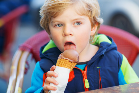 Little blond toddler child eating chocolate ice cream.の写真素材