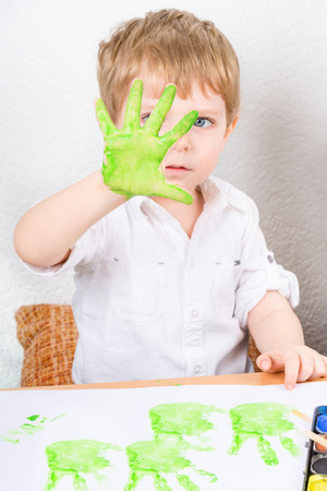 Funny child having fun with making handpaints with colors at home. Creative leisure for family and kids.の写真素材