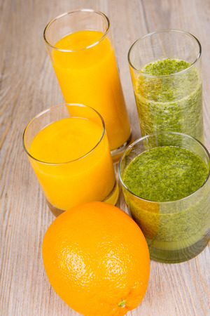 Fresh orange and spinach smoothie drink. On wooden background. Healthy bio organic vegan drink.の写真素材