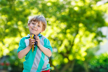 Little kid boy playing with car toy in summer garden. Active outdoors leisure for children on hot summer sunny day. Family lifestyleの写真素材