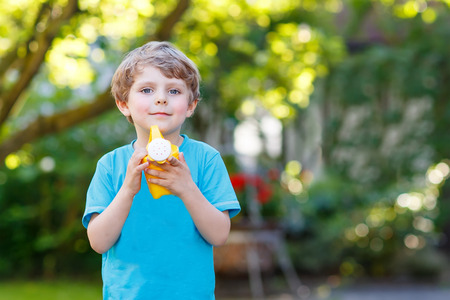 Little blond kid boy playing with water can toy in summer garden. On warm summer day, happy leisure with children outdoors.の写真素材