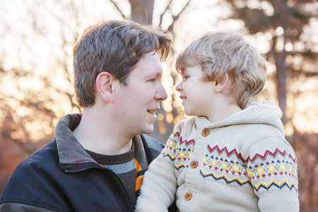 Father and little son in park or forest, outdoors. Hugging and having fun together.の写真素材