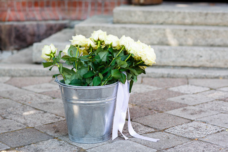 Bouquet of white roses for decoration of a wedding, standing in bucket, by a protestant churchの写真素材