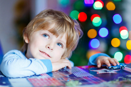 Little blond child playing with cars and toys at home, indoor. Cute happy funny boy having fun with...