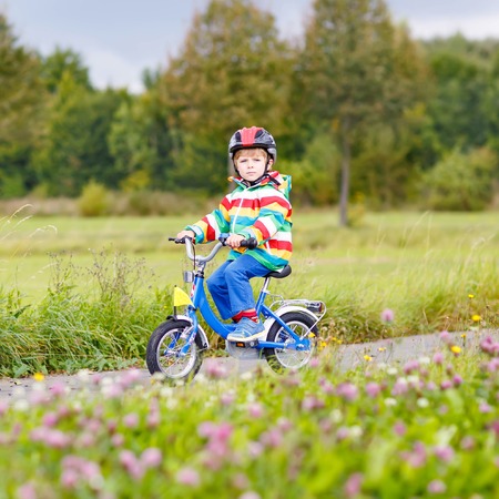 Adorable preschool boy riding on bike on warm autumn day. Countryside. Child in helmet. Active leisure and sports for kids.の写真素材