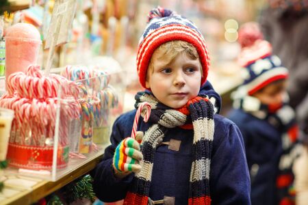Little cute kid boy near sweet stand with candy canes. Happy child on Christmas market in Germany. Traditional leisure for families on xmasの写真素材