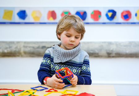 Little child playing with lots of colorful plastic blocks kit indoor. kid boy having fun with building and creating geometric figures.の写真素材