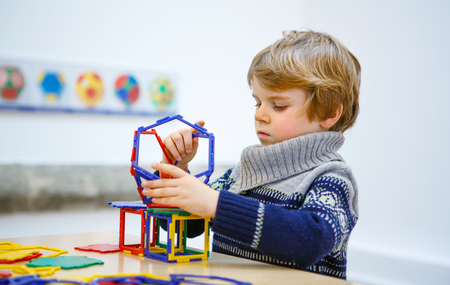 Little child playing with lots of colorful plastic blocks kit in maths  . kid boy having fun with building and creating geometric figures.の写真素材