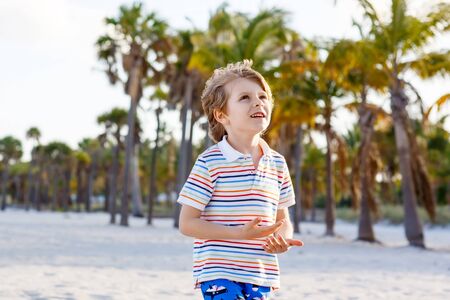 Adorable active little kid boy having fun on Miami beach, Key Biscayne. Happy cute child smiling and laughing at the camera and having dreams.の写真素材
