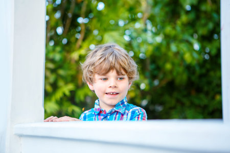 Portrait of little blond kid boy, smiling at the camera. Happy cute child relaxing and enjoying...
