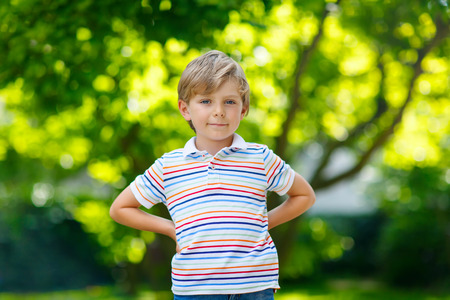 Portrait of little blonde preschool kid boy in summer. Child with green backgrounds on warm summer day. Happy carefree childhood.の写真素材