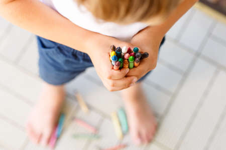 Closeup of child's hands with lots of colorful wax crayons pencils. Kid preparing stationary and student stuff. Back to school conceptの写真素材