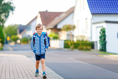 Happy little kid boy with glasses and backpack or satchel on the way to school or nursery. Child outdoors on warm sunny day, Back to school, education conceptの写真素材