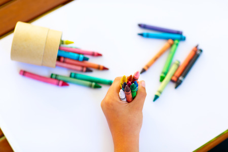 Closeup of child's hands with lots of colorful wax crayons pencils. Kid preparing stationary and student stuff. Back to school conceptの写真素材