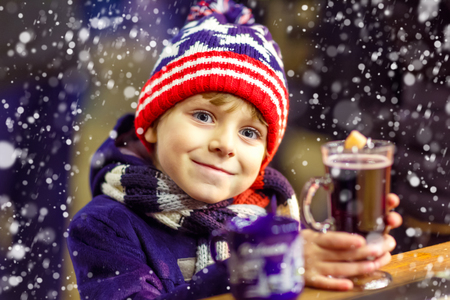 Little cute kid boy with cup of steaming hot chocolate or children punch. Happy child on Christmas market in Germany. Traditional leisure for families on xmasの写真素材