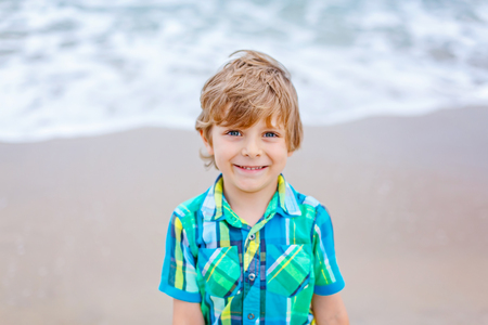 Portrait of happy little kid boy on the beach of ocean. Funny cute child making vacations and enjoying summer.の写真素材