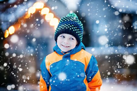 Happy kid boy having fun with snow in winterの写真素材
