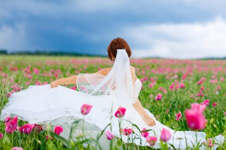happy bride in white dress  having fun in flower poppy fieldの写真素材