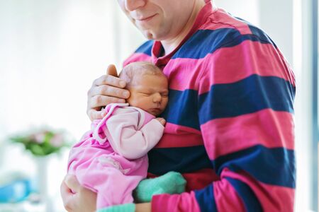 Happy proud young father holding his sleeping newborn baby daughterの写真素材