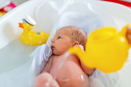 Cute adorable newborn baby taking first bath.の写真素材