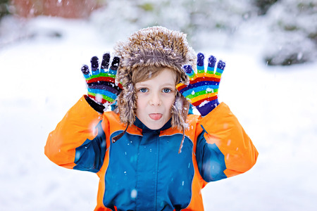 Happy kid boy having fun with snow in winterの写真素材