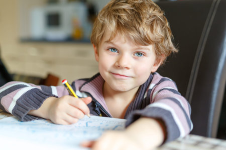 Happy school kid boy at home making homework
