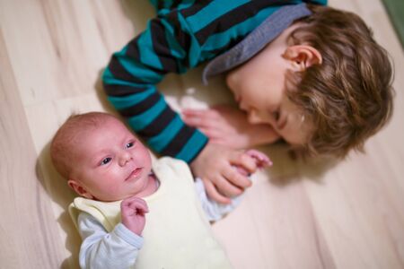 Happy little kid boy with newborn baby sister girlの写真素材