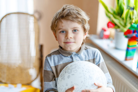 Little blond preschool kid boy with air balloon ball