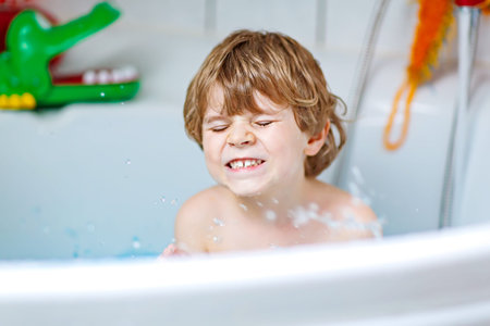 cute little kid boy playing with soap in bathtub