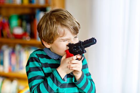 Cute little preschool kid boy playing with gun at home,の写真素材