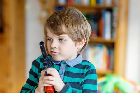 Cute little preschool kid boy playing with gun at home,の写真素材