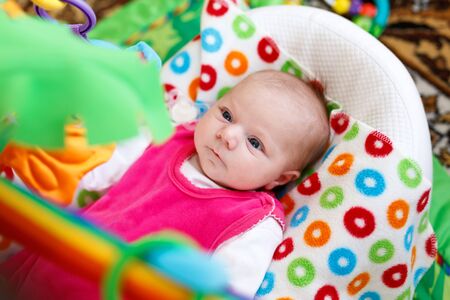 Cute adorable newborn baby playing on colorful toy gymの写真素材