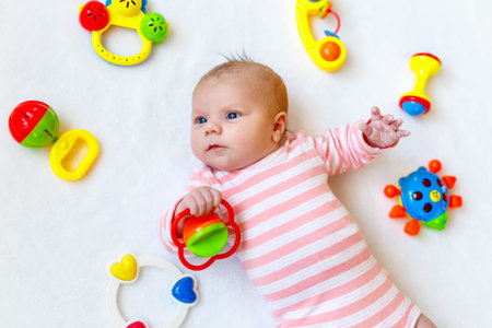 Cute baby girl playing with colorful rattle toys