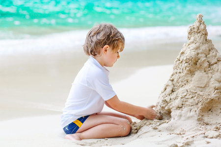 Little kid boy building sand castle on tropical beachの写真素材