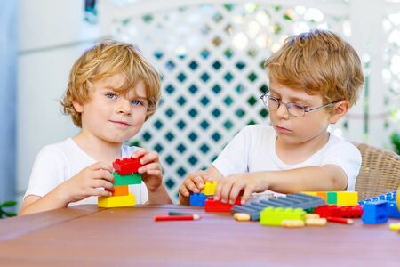 Two little kid boys playing with plastic blocks togetherの写真素材