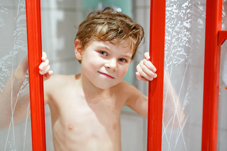 Happy little kid boy in the shower cabin wet and smiling.の写真素材