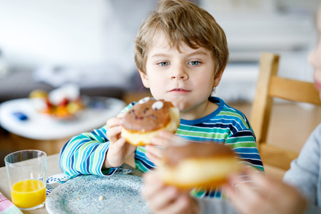 Adorable little preschool boy eating donut indoorの写真素材