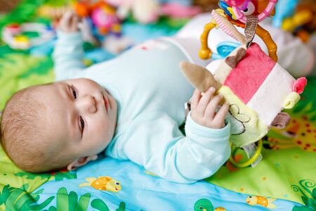 Cute adorable newborn baby playing on colorful toy gymの写真素材