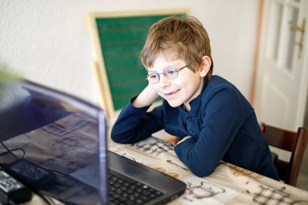 kid boy with glasses making preschool homework on computer