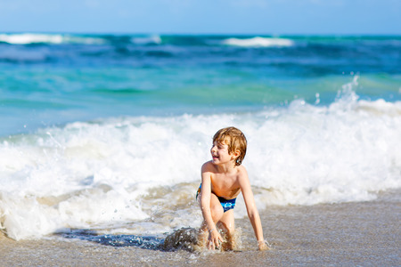 little blond kid boy having fun on ocean beach in Floridaの写真素材