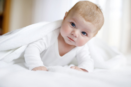 Baby girl wearing white towel or winter overal in white sunny bedroomの写真素材