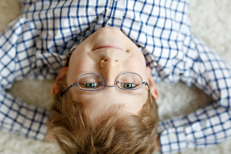 Close-up portrait of little blond kid boy with brown eyeglassesの写真素材