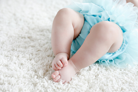 Close-up of legs and feet of baby girl on white background wearing turquoise tutu skirt.の写真素材