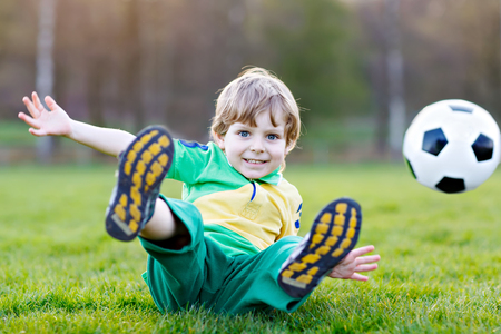Little cute kid boy of 4 playing soccer with football on field, outdoorsの写真素材