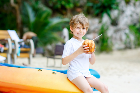 Little kid boy drinking coconut juice on tropical beachの写真素材
