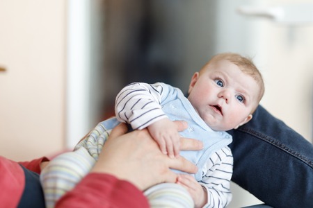 Happy proud young father having fun with newborn baby daughter, family portrait togehter. Dad with baby girl, love. New born child looking on dad. Bonding, family, new lifeの写真素材